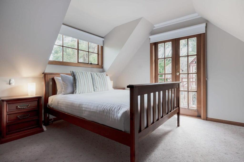 1 dormitorio con 1 cama y algunas ventanas en Gracelands Swiss Inspired Home with Gorgeous Grounds, en Hadspen