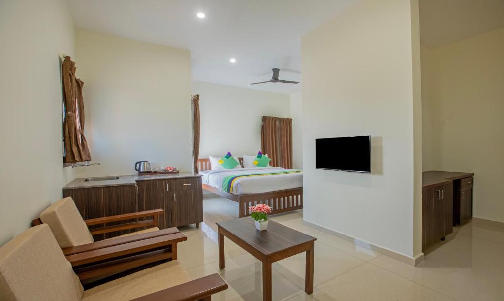 Cette chambre comprend une chambre avec un lit et une télévision. dans l'établissement Treebo Trend Samanvaya Retreat - Mysore, à Mysore