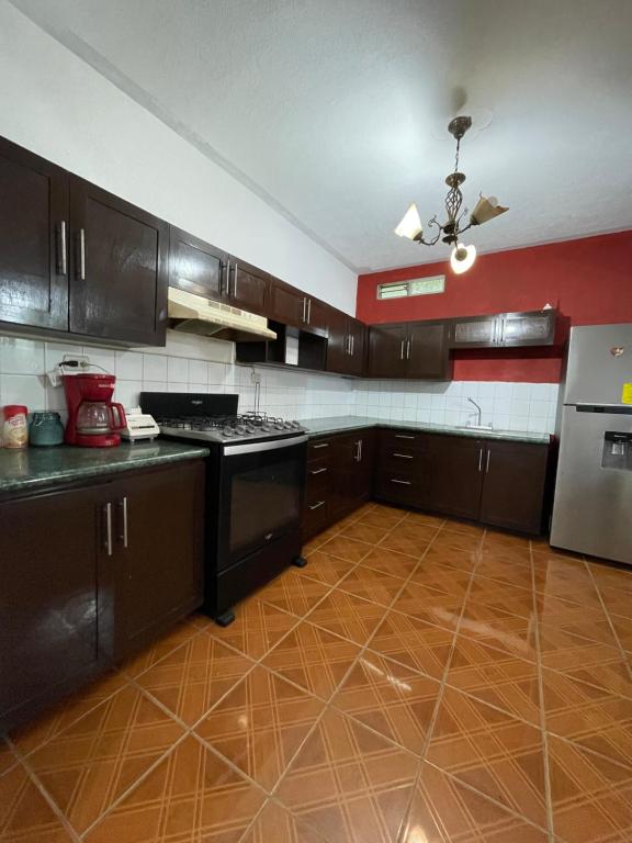 La cuisine est équipée de placards bruns et d'un four avec plaques de cuisson. dans l'établissement Casa genesis, à Panajachel