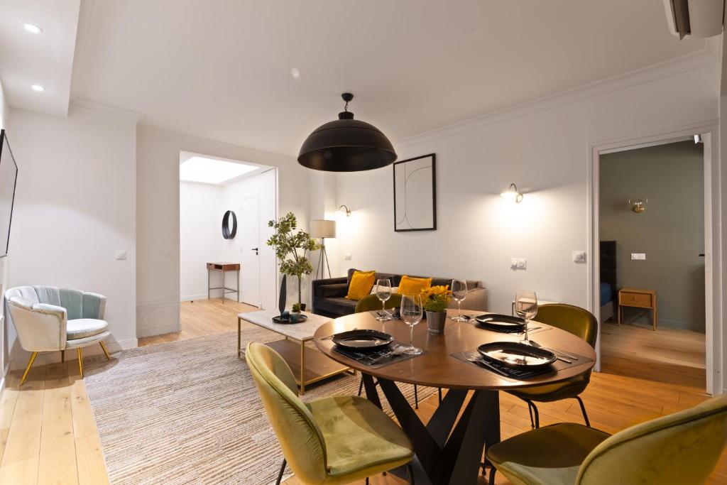 a dining room and living room with a table and chairs at Appartement Quartier Arc de Triomphe 4 in Paris
