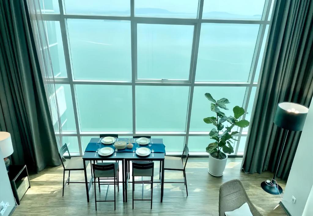 a dining room with a table and chairs and a large window at Maritime Seaview Suites Penang in George Town