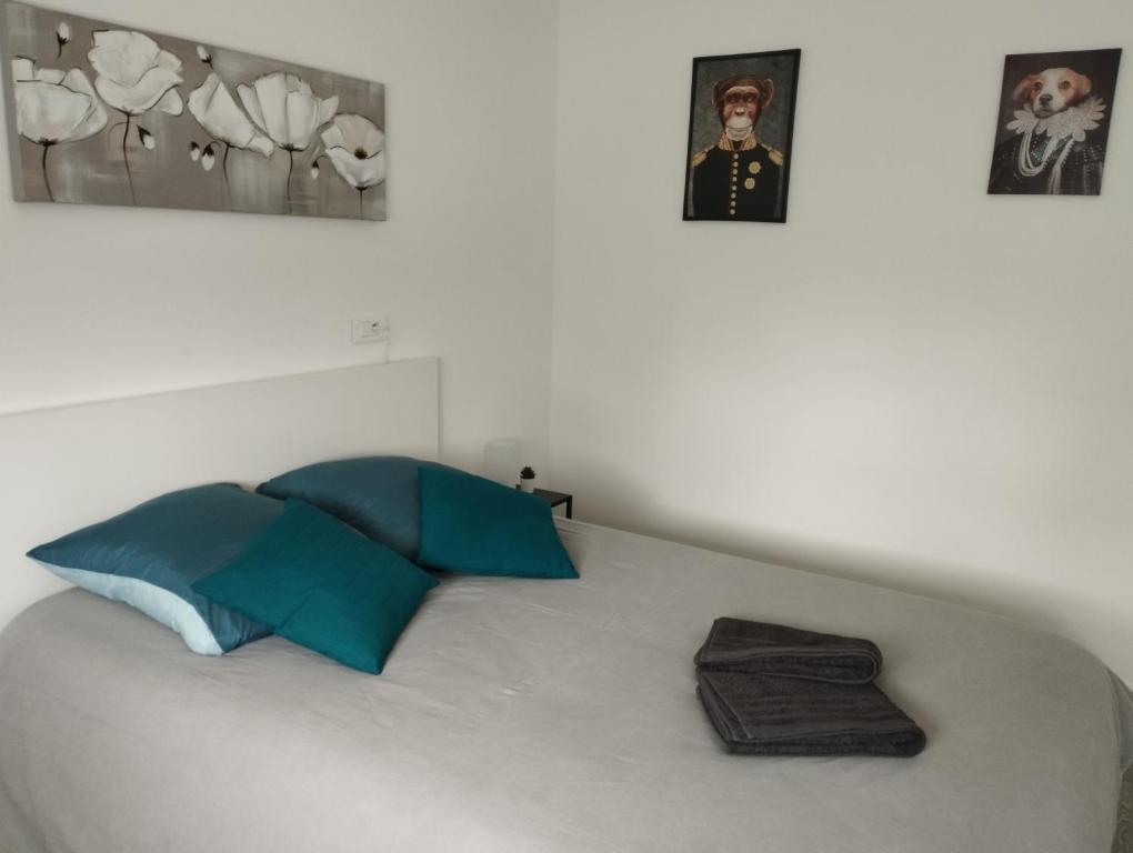 a white bed with blue pillows and pictures on the wall at La Bellière in Saint-Florent-le-Vieil