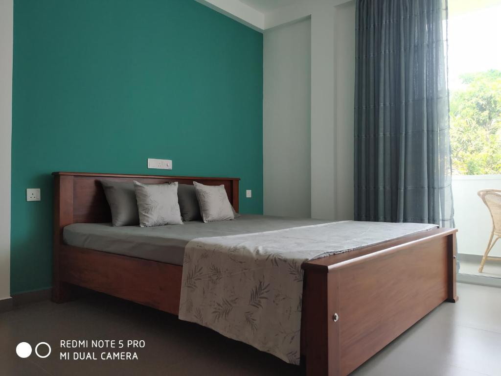 a bed in a bedroom with a blue wall at Coastal Cloud in Hikkaduwa