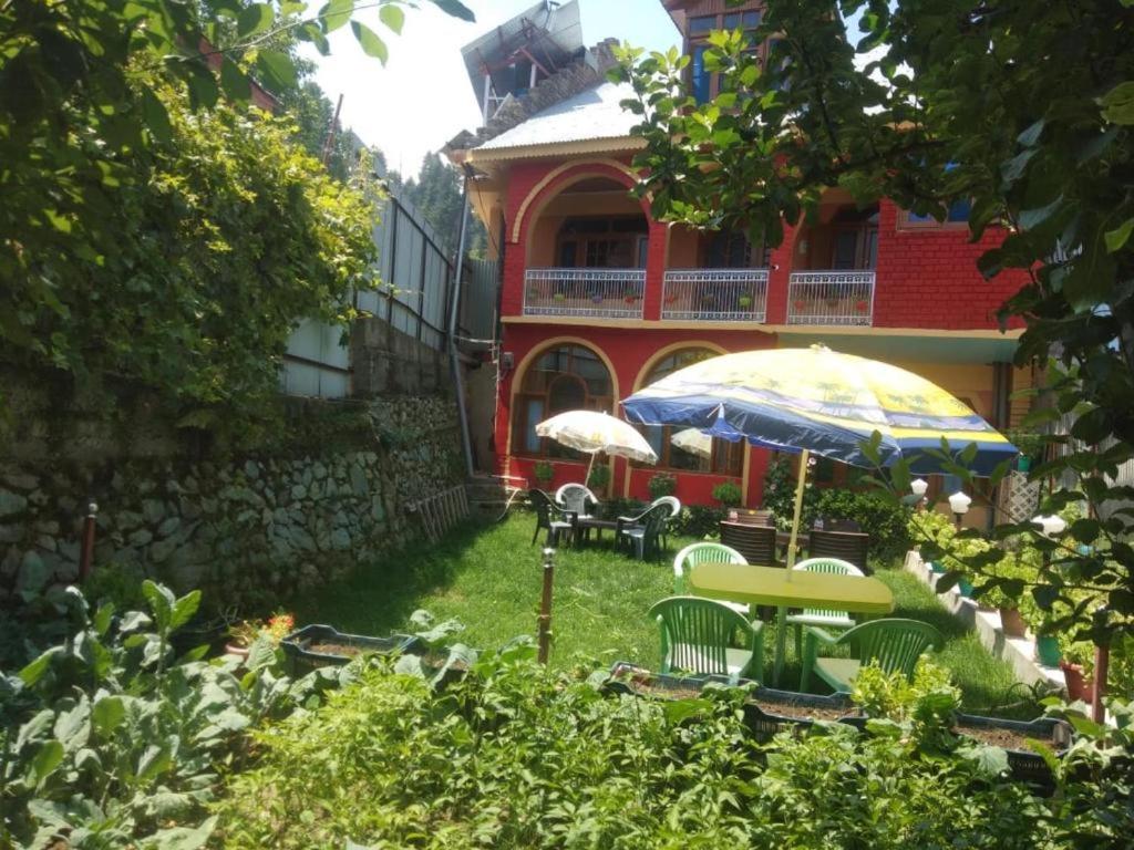 un patio con mesas y sombrillas frente a un edificio en WANI GUEST HOUSE, en Gulmarg