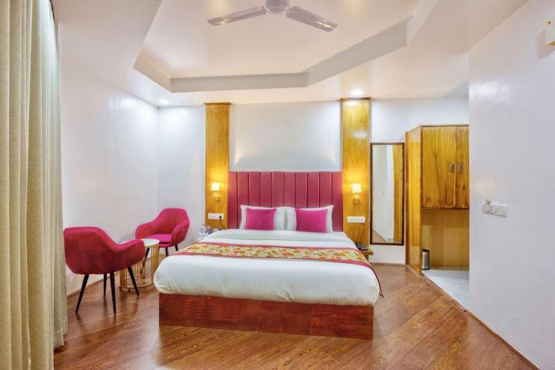 a bedroom with a large bed and two red chairs at Astra Luxury Rooms and Cafe in Varanasi