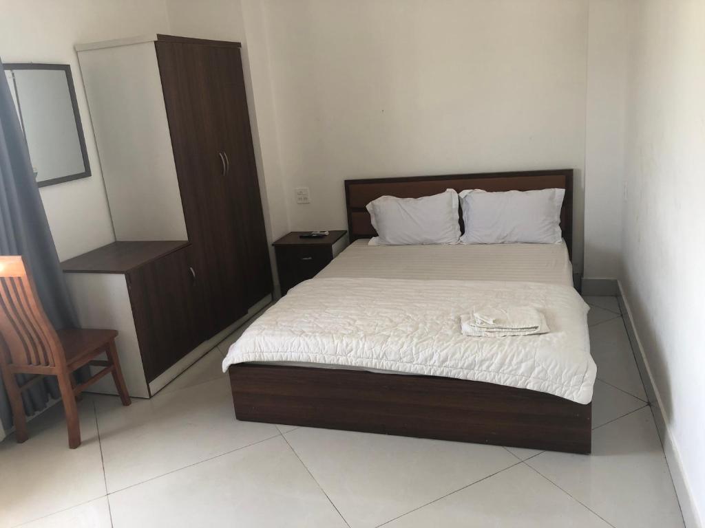 een slaapkamer met een bed met een dressoir en een stoel bij Kiều Thủy Hotel in Bao Loc