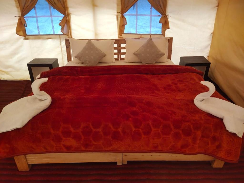 - une chambre avec un grand lit rouge et deux fenêtres dans l'établissement Northern Valley Camp - Nubra, à Hundar