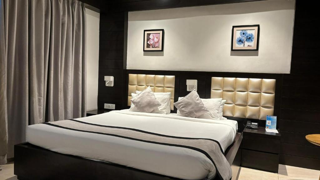 a bedroom with a large bed with white sheets and pillows at Wonder Country-Club in Barādiha