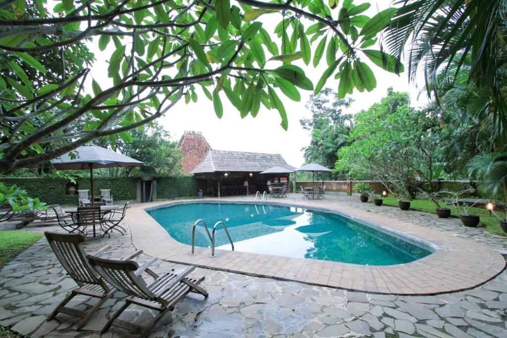 烏干蘭的住宿－Hills Joglo Villa，一个带两把椅子和一张桌子的游泳池