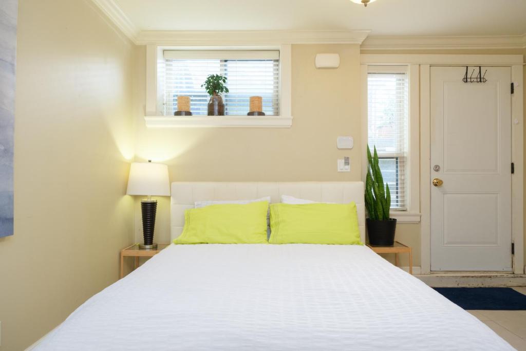 una camera da letto con un letto con lenzuola bianche e cuscini gialli di Oakridge Cozy Guesthouse a Vancouver