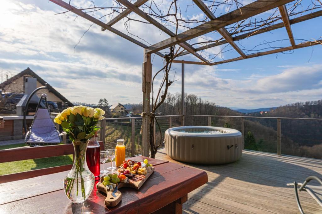 a table with flowers on a deck with a hot tub at Vineyard Cottage Sunny Hill - Happy Rentals in Mirna