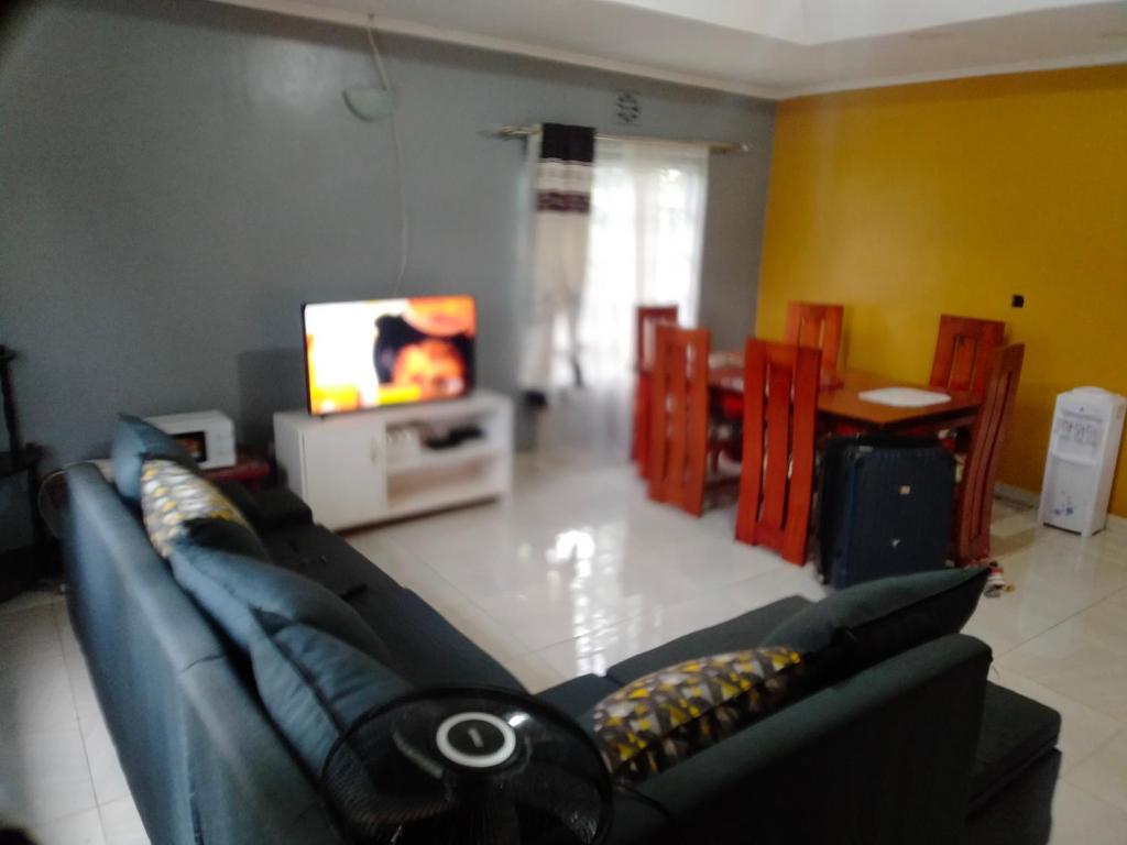 a living room with a blue couch and a tv at Plush 3 Bedroom Apartment Home in Kitale