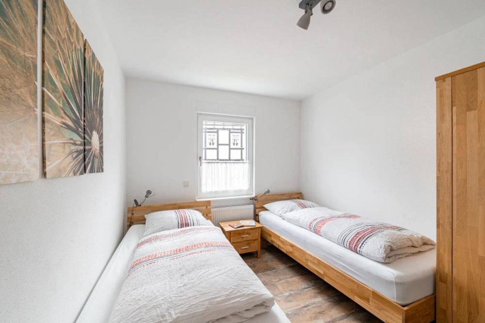 2 Betten in einem Zimmer mit weißen Wänden und einem Fenster in der Unterkunft Ferienwohnung Haus An der Lenne in Lennestadt