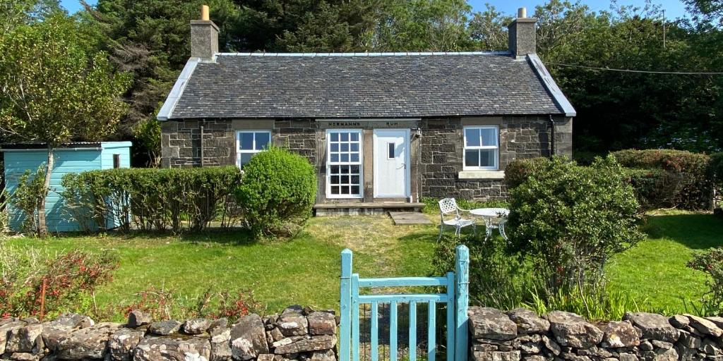- un petit cottage en pierre avec un banc bleu devant dans l'établissement Normanns Ruh, à Ballygown