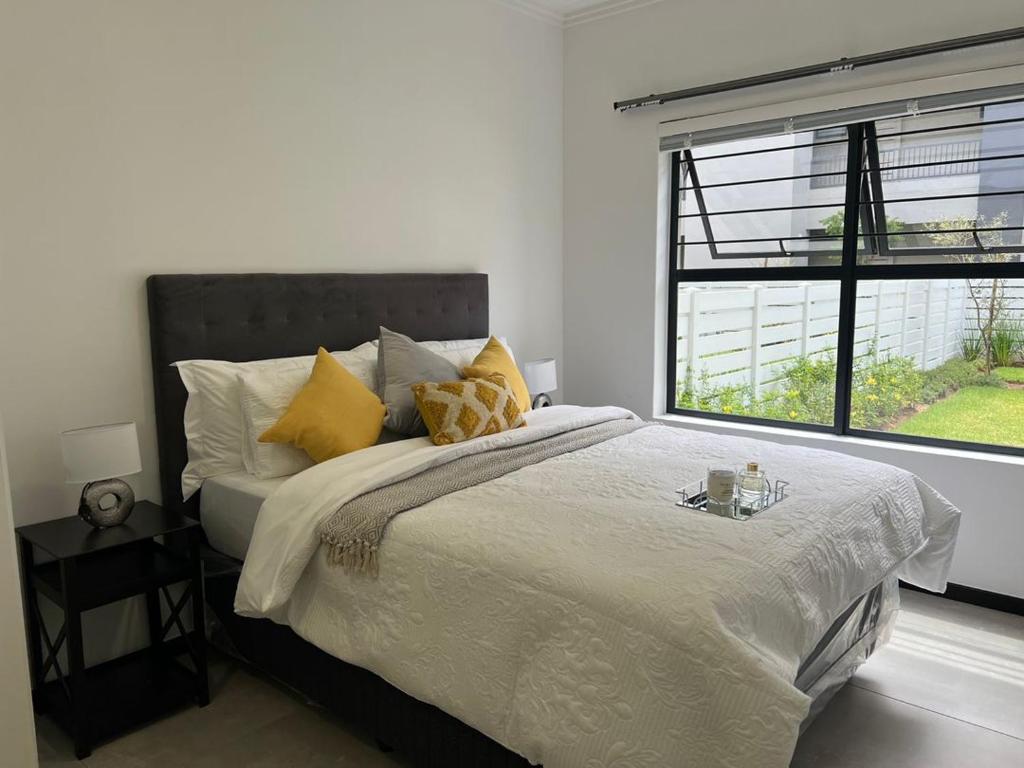 a bedroom with a bed with yellow pillows and a window at Tocara Lifestyle Estate: Fourways in Johannesburg