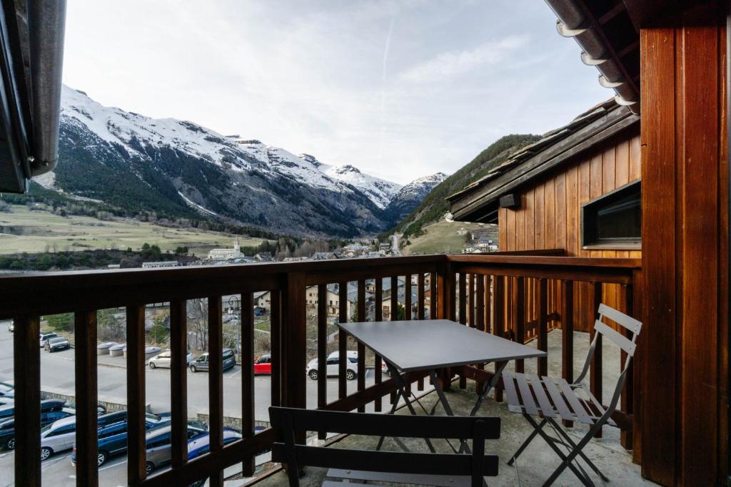 a balcony with a table and chairs and mountains at Appartement Front De Neige in Termignon