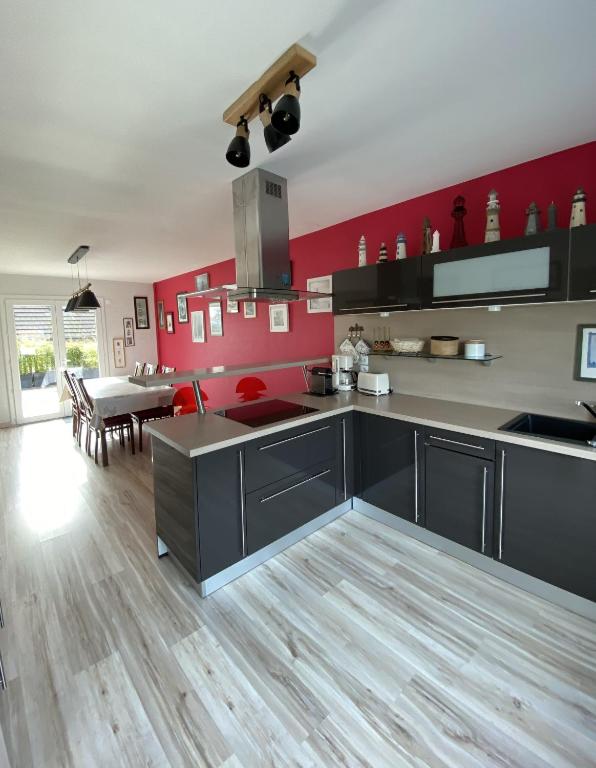 a kitchen with black cabinets and a red wall at La Maison des phares in Lion-sur-Mer
