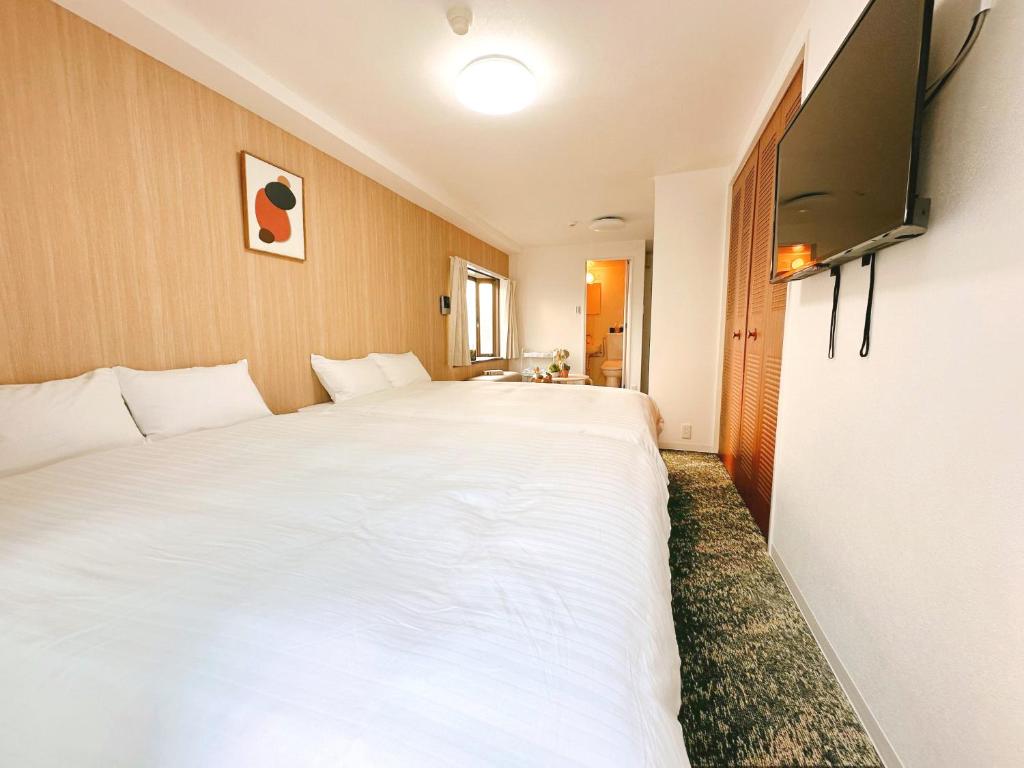 - une chambre avec un grand lit blanc et une télévision à écran plat dans l'établissement Tutulu502, à Osaka