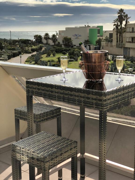 - une table avec deux verres de vin sur le balcon dans l'établissement Village Naturiste Le Cap d’Agde Heliopolis Sud Vue Mer, au Cap d'Agde