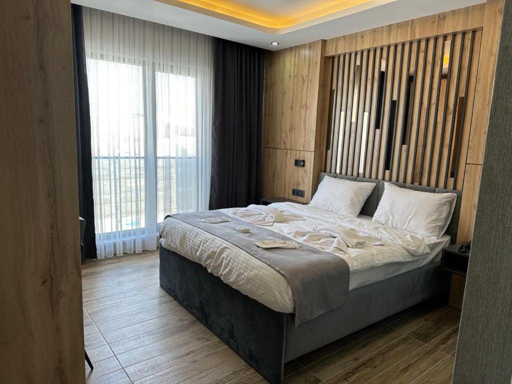 a bedroom with a large bed and a large window at world say hotel in Bostaniçi