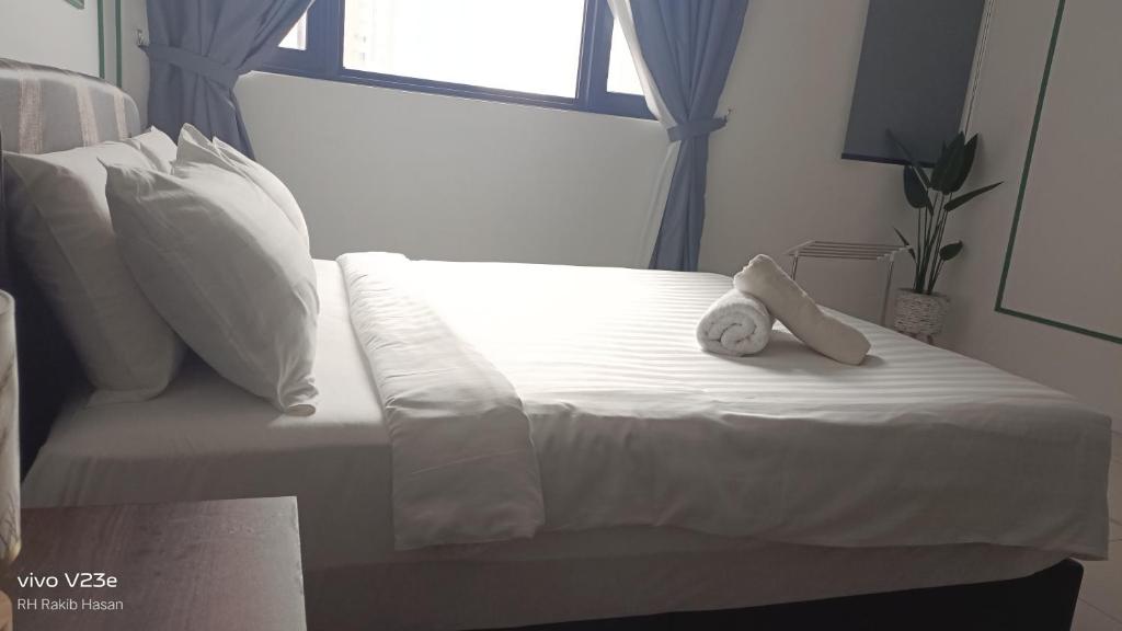 una cama blanca con un osito de peluche sentado en ella en Flyline suite at Axon residence KLCC en Kuala Lumpur