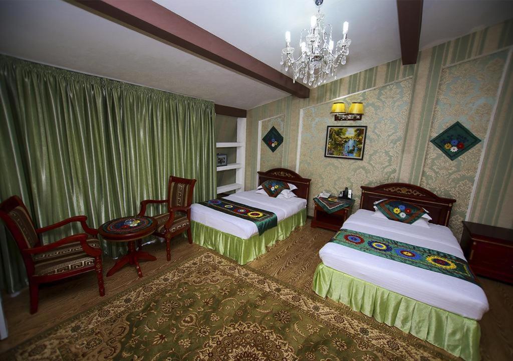 a bedroom with two beds and a chair and a chandelier at ORIYO DUSHANBE HOTEL in Dushanbe