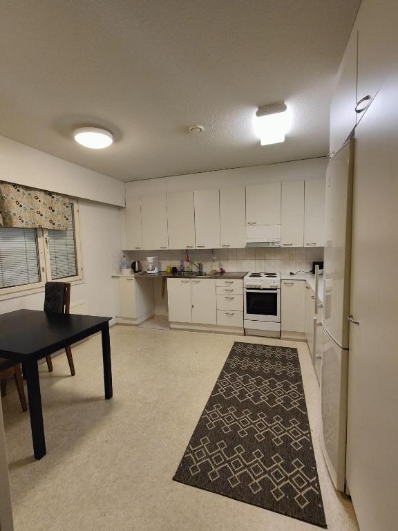 una cocina con armarios blancos y una mesa con alfombra en Ketola Apartments Reisjärvi, en Reisjärvi