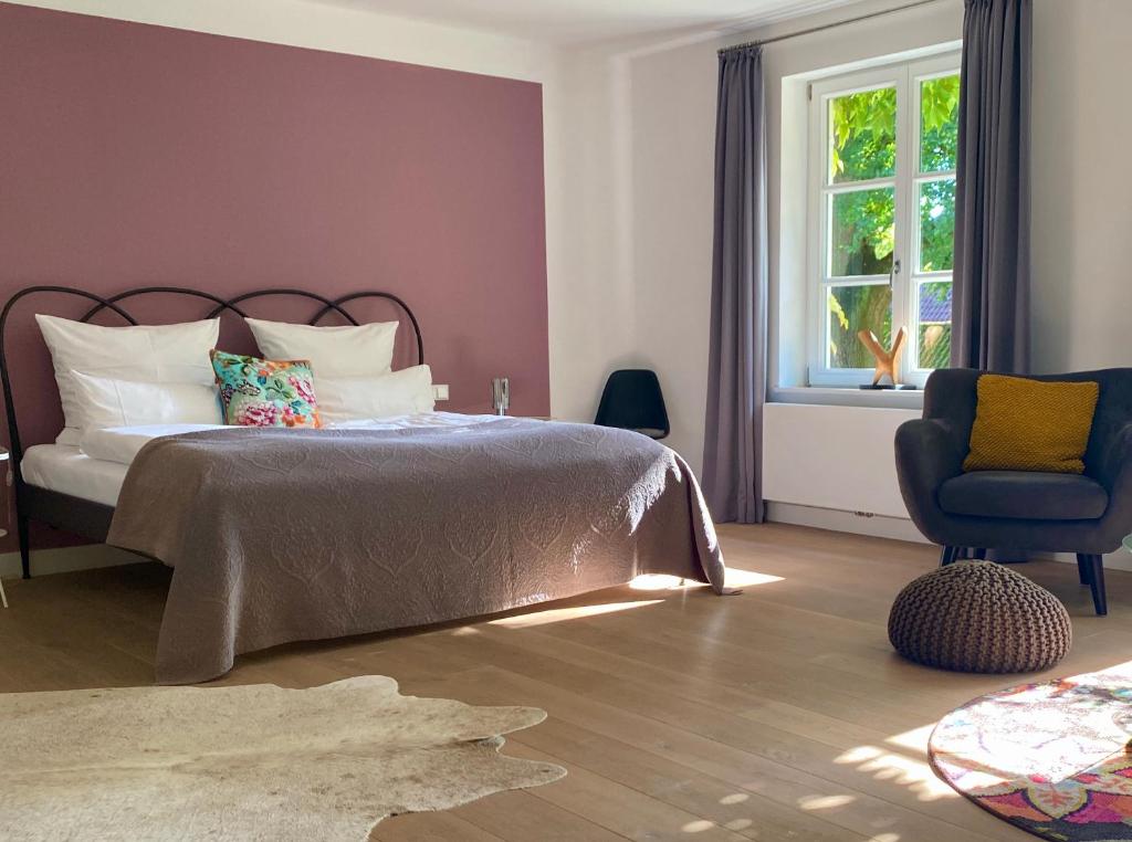 una camera con un letto e una sedia e una finestra di Hotel Altes Dichterhaus a Timmel