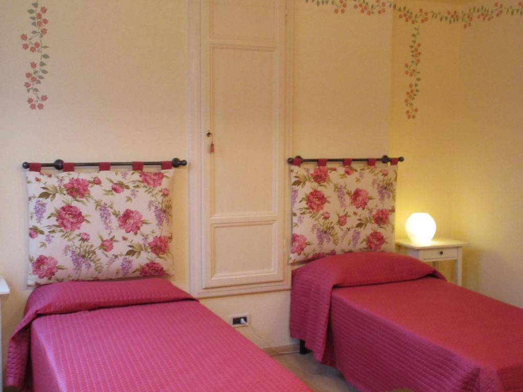 dwa łóżka w pokoju z różowymi prześcieradłami w obiekcie Mimì Apartment w Lukce