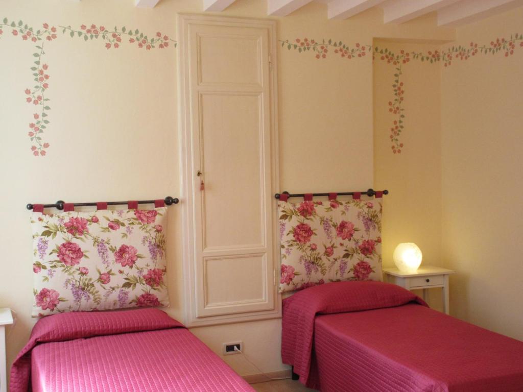 duas camas num quarto com lençóis cor-de-rosa em Mimì Apartment em Lucca