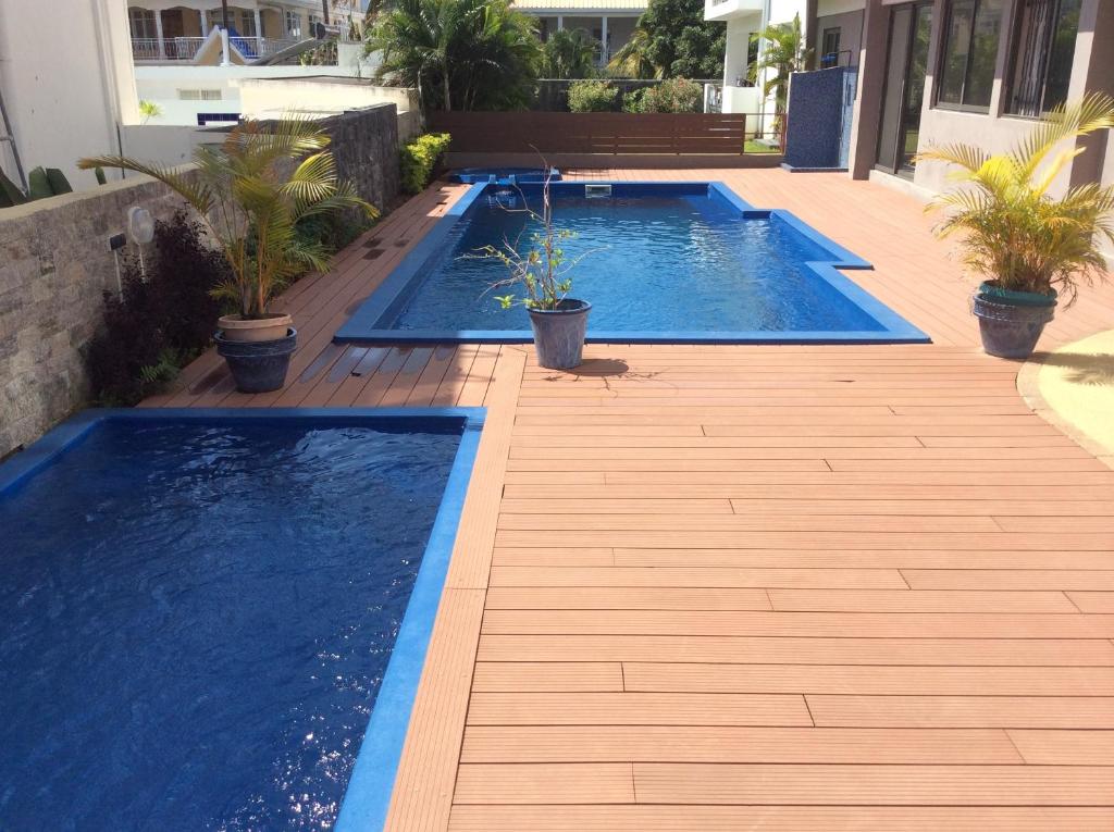 two swimming pools on a wooden deck with potted plants at Fortuna Beach in Flic-en-Flac