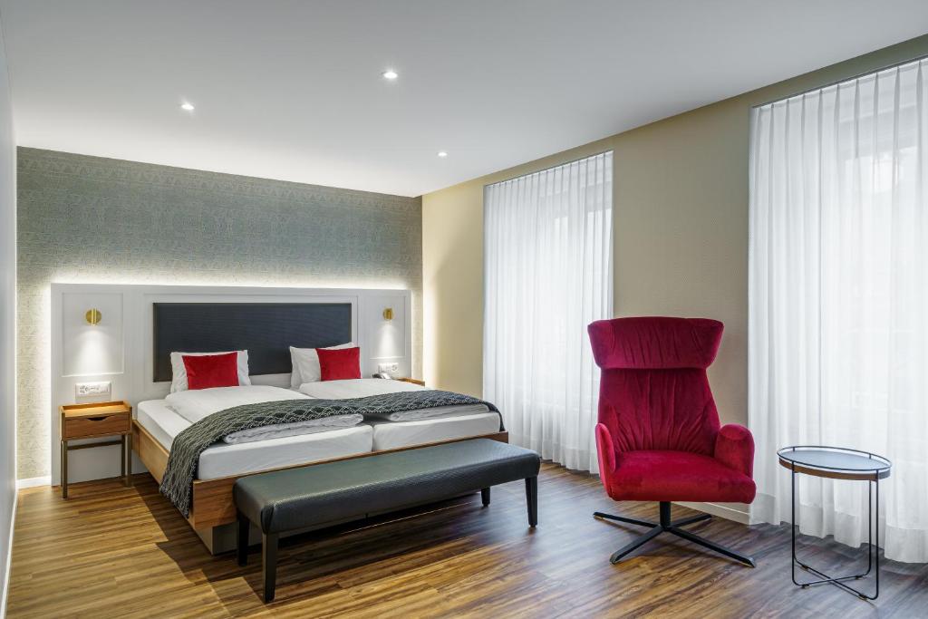 インターラーケンにあるHotel Du Nordのベッドと赤い椅子のある寝室