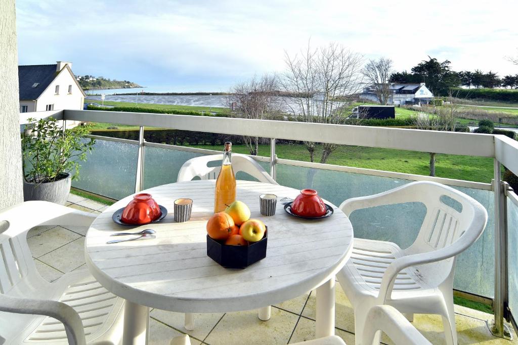 - une table avec une bouteille de vin et des fruits sur un balcon dans l'établissement Cocon en bord de mer - Appt vue mer, à Saint-Cast-le-Guildo