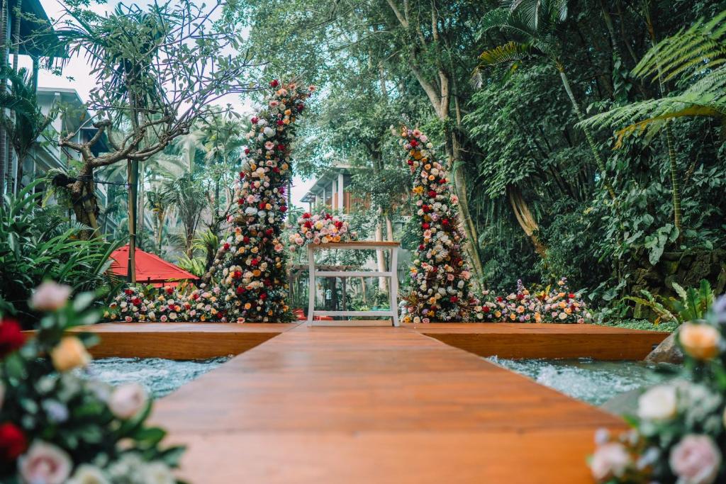 a wooden path in a garden with flowering plants at AnandaDara Ubud in Ubud