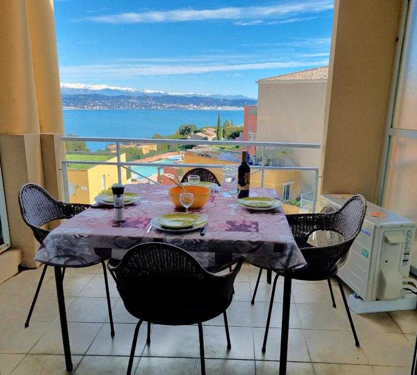 - une table à manger avec des chaises et une vue sur l'océan dans l'établissement Petit écrin vue Mer et Montagne, à Théoule-sur-Mer