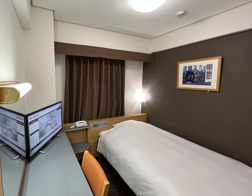 een hotelkamer met een bed en een flatscreen-tv bij Hotel Alpha-One Mishima in Mishima