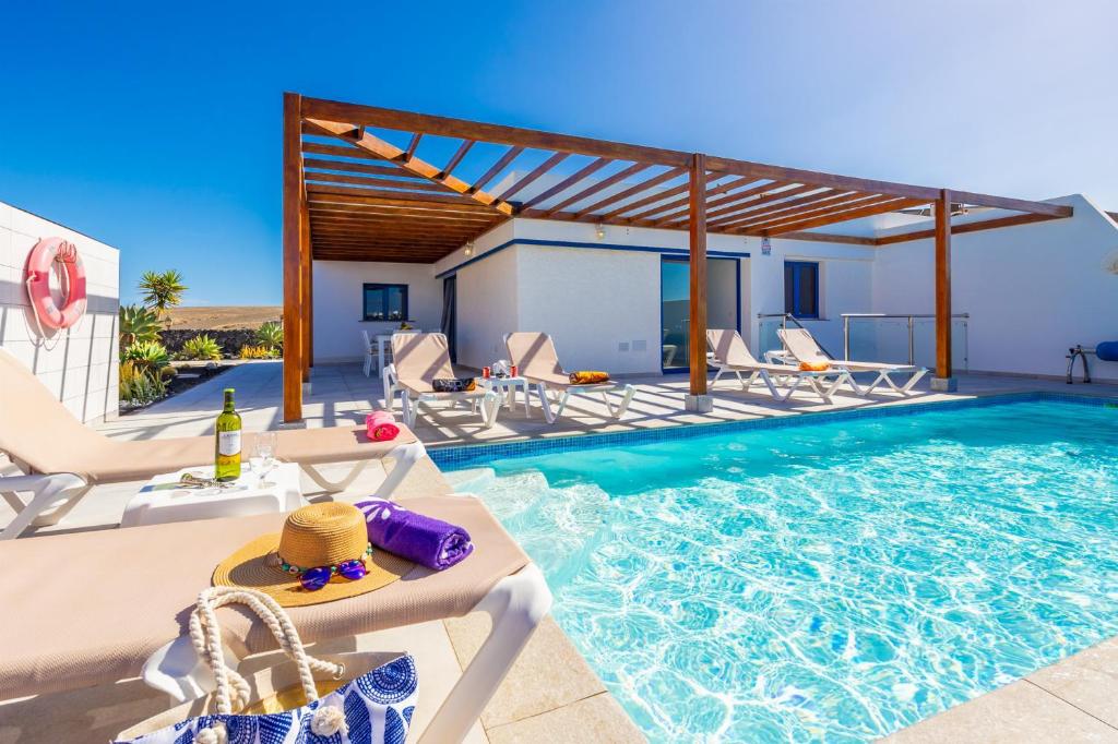einen Pool mit Liegestühlen und einem Pool in der Unterkunft Villa Beyond in Playa Blanca