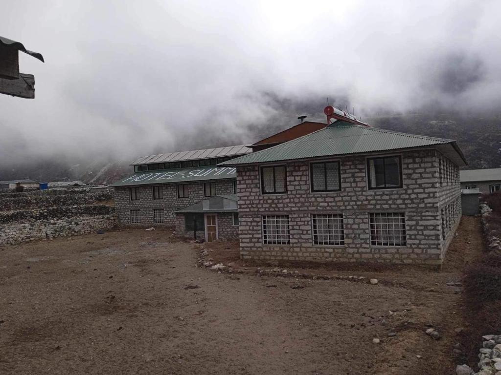 a building on a hill with clouds in the background at Hotel Summit in Dingboche