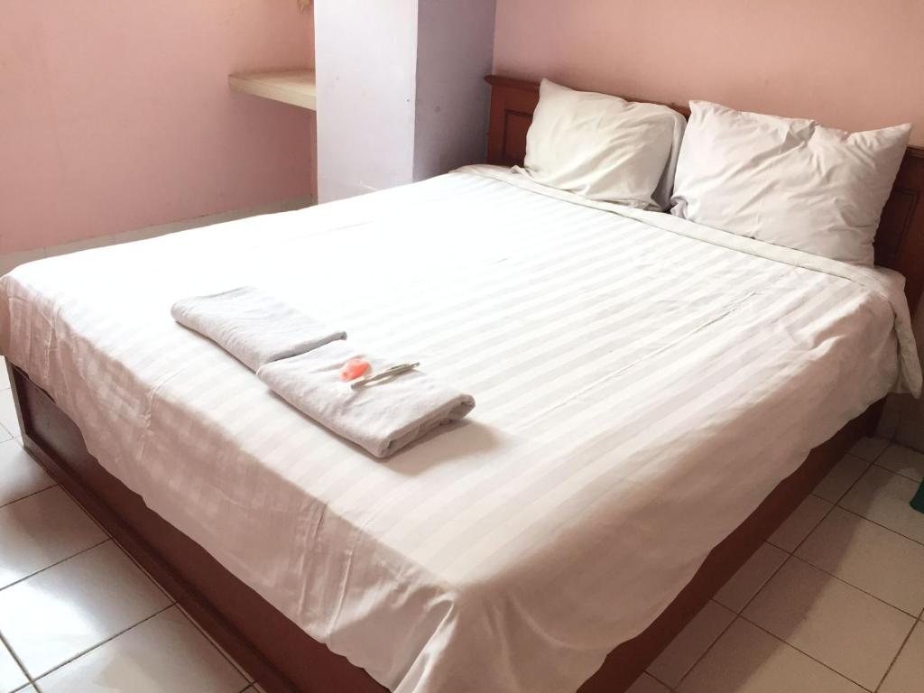 ein Bett mit weißer Bettwäsche und einem Handtuch darauf in der Unterkunft Griya Mitra Kost in Jakarta