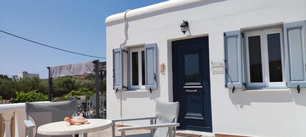 ein weißes Haus mit einer blauen Tür und einem Tisch in der Unterkunft Chrysiis House 1 in Maltezana