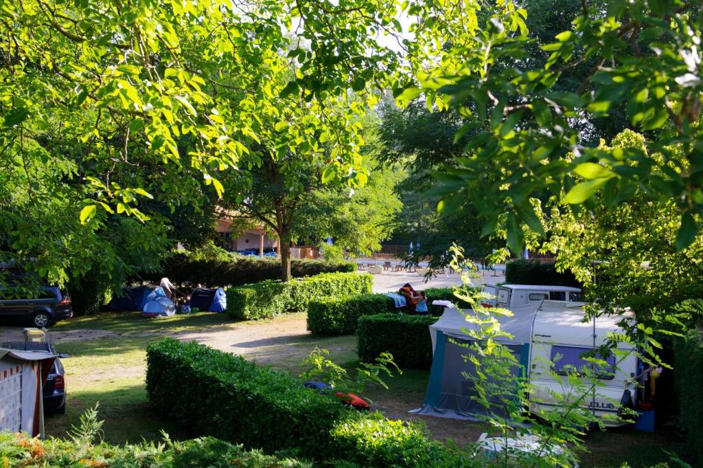 un jardin avec une table blanche, des arbres et des buissons dans l&#39;établissement Camping Les Mijeannes, à Rieux-de-Pelleport