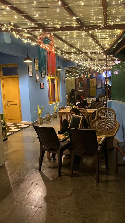 達蘭薩拉的住宿－Alora bhagsu，餐厅设有桌椅和天花板上的灯光