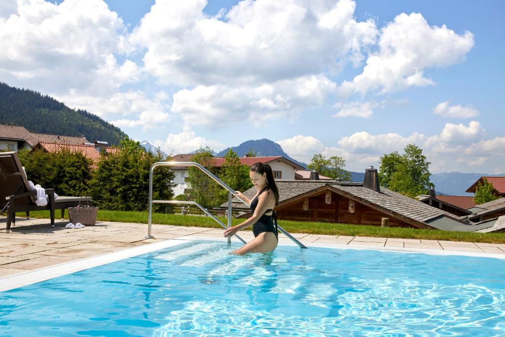 una mujer está jugando en una piscina en Alpin Lodges - Moderne Appartements mit Zugang zu 3000 qm SPA Panoramahotel Oberjoch, en Bad Hindelang