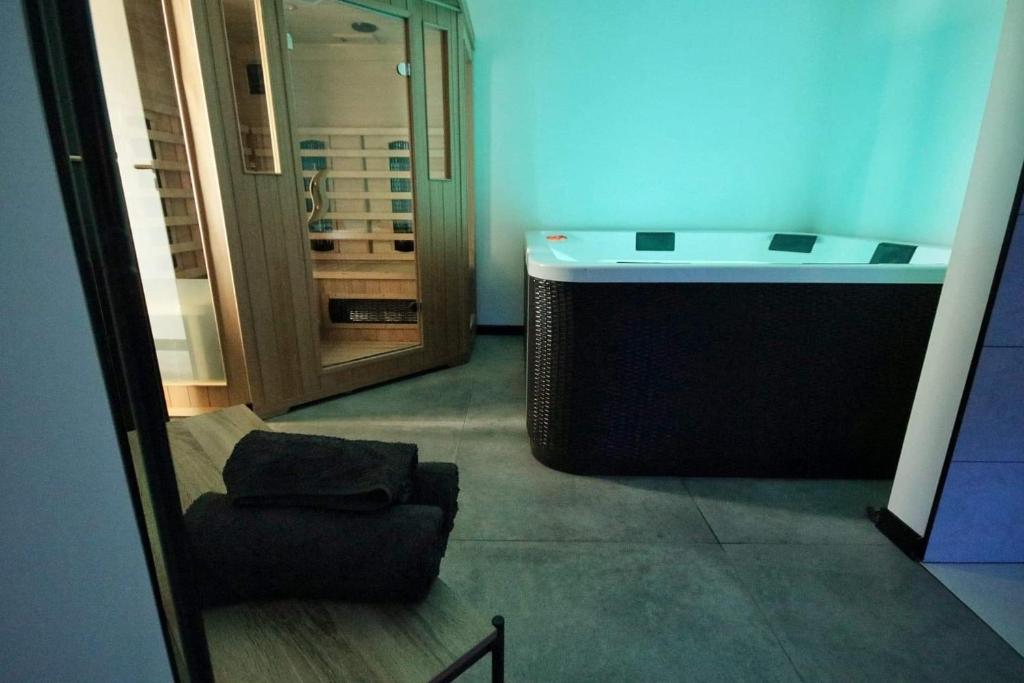 bañera en una habitación con silla y taburete en La Brique, en Yvetot Bocage