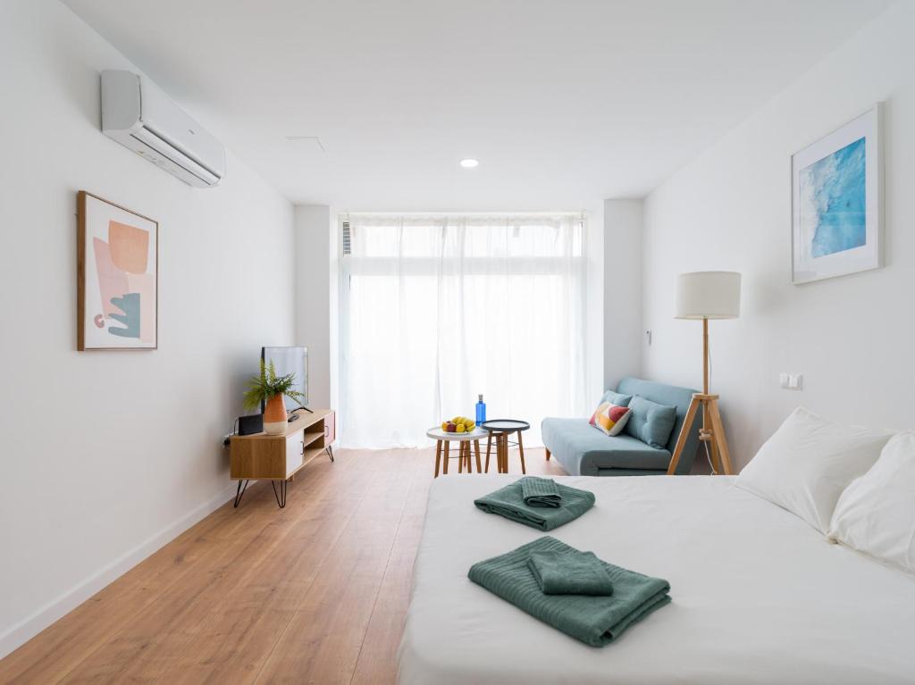 1 dormitorio blanco con 1 cama y sala de estar en HomeForGuest Estudio Brisa Canteras con terraza, en Las Palmas de Gran Canaria