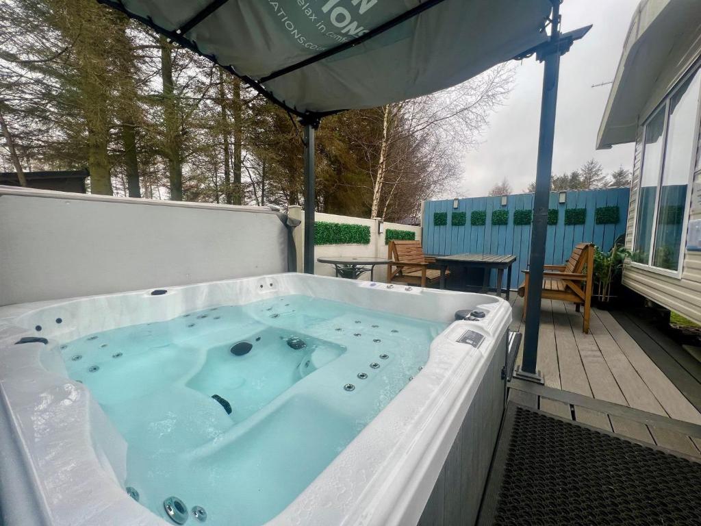 bañera de hidromasaje en un patio con sombrilla en Private Hot Tub Cabin, Pergola and Large Decking Area, en Swarland
