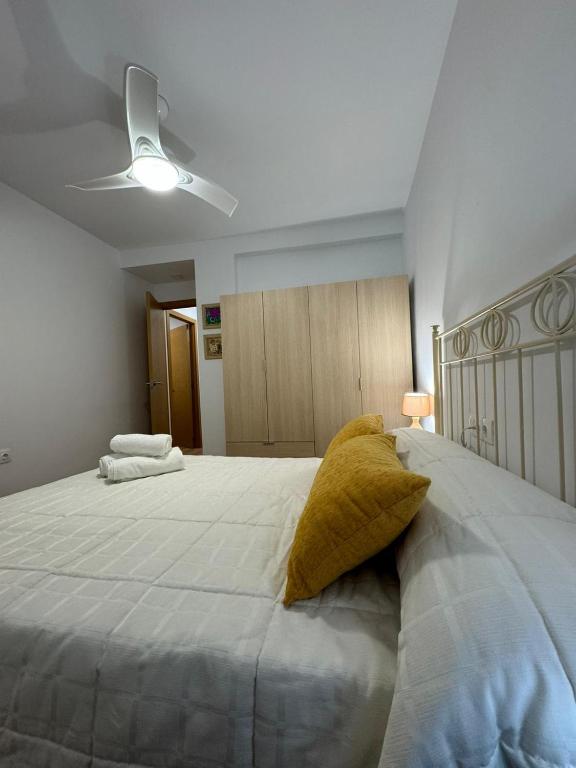 1 dormitorio con 1 cama blanca grande con almohadas amarillas en Apartamento Irene 2 en Caravaca de la Cruz