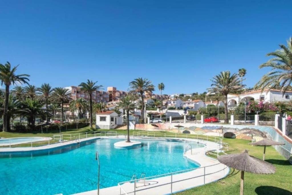 a large swimming pool with palm trees in a resort at Beach and Golf House Sotogrande - Torreguadiaro in Torreguadiaro
