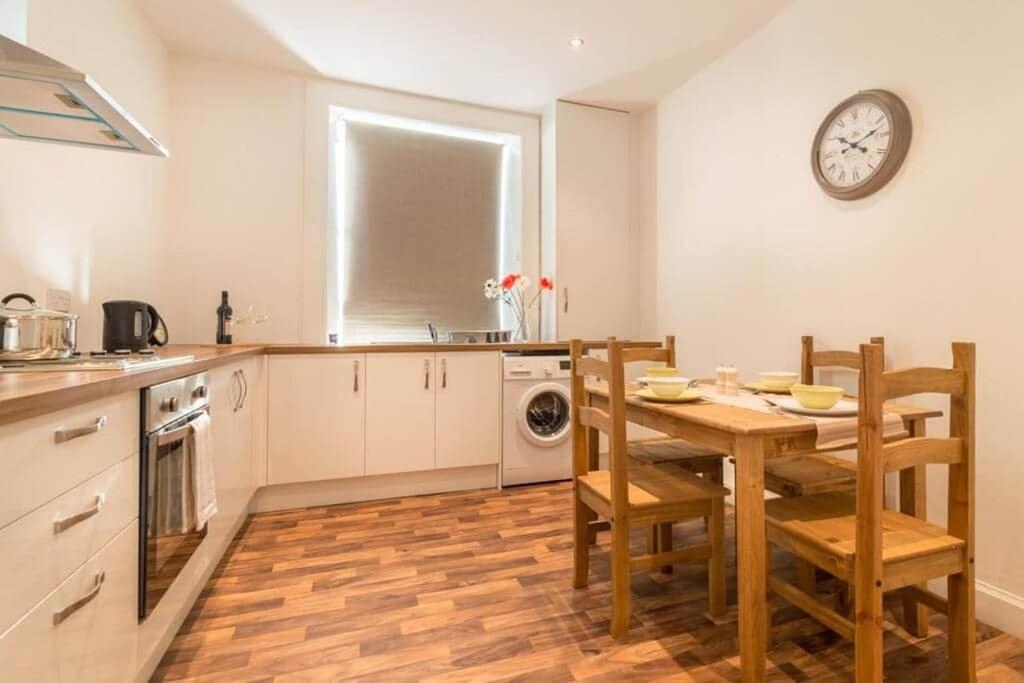 a kitchen with a table and chairs and a clock on the wall at River View in Hawick