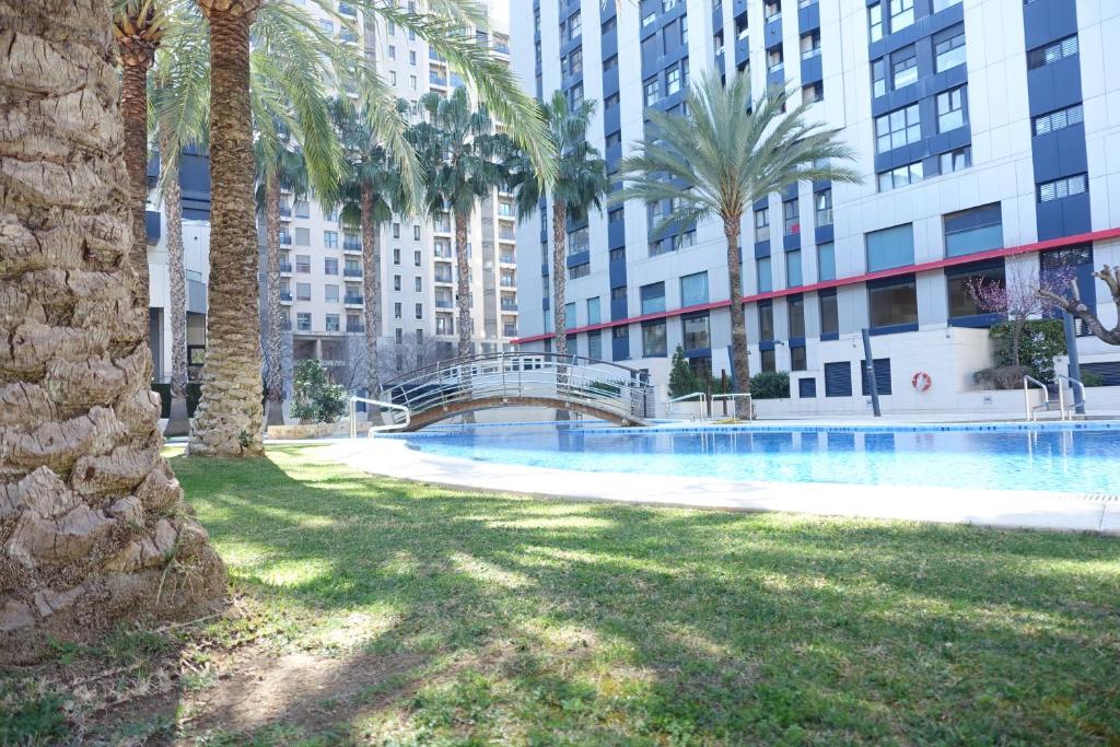 uma piscina com palmeiras e uma ponte em Palau de Congressos Great Stay Room em Valência